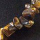 18" choker of approximately 10mm chunky style Tiger Eye chips with lobster claw clasp and 1.5" adjustable chain. 